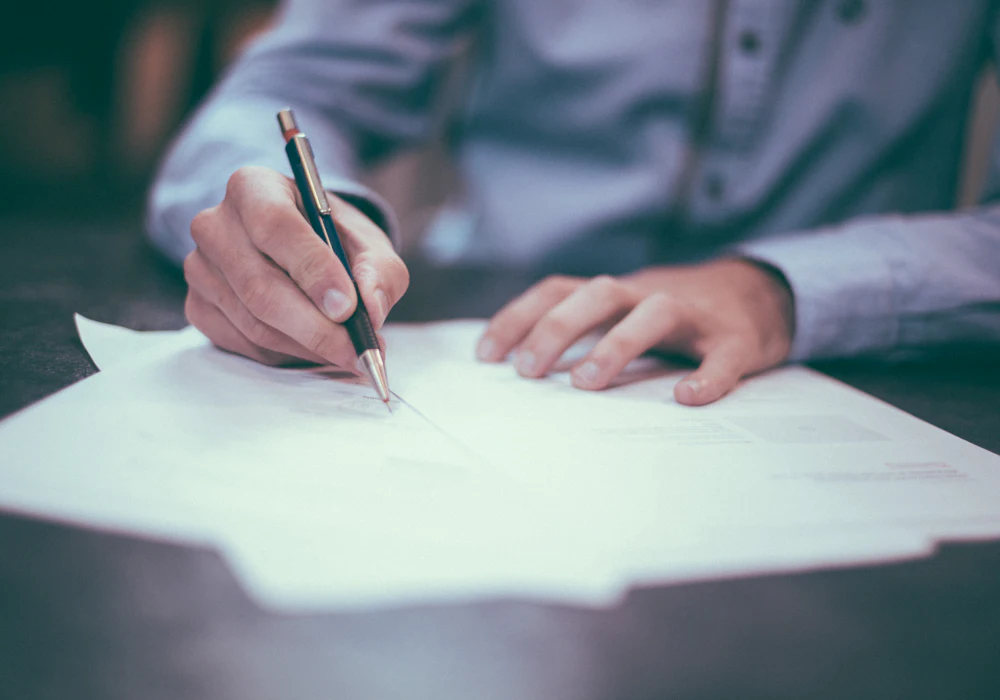 A person signing a printed agreement with a pen
