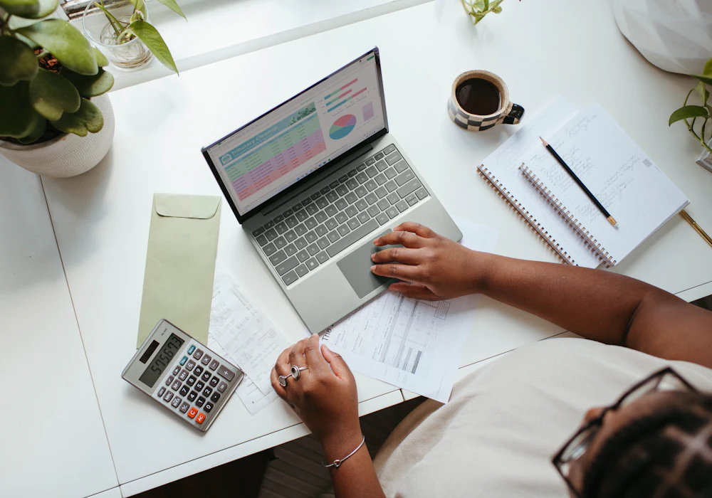 A laptop, calculator and paperwork used to prepare a written quotation