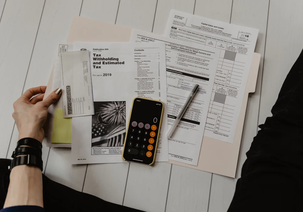 Payroll paperwork, a calculator and a pen laid out on a desk