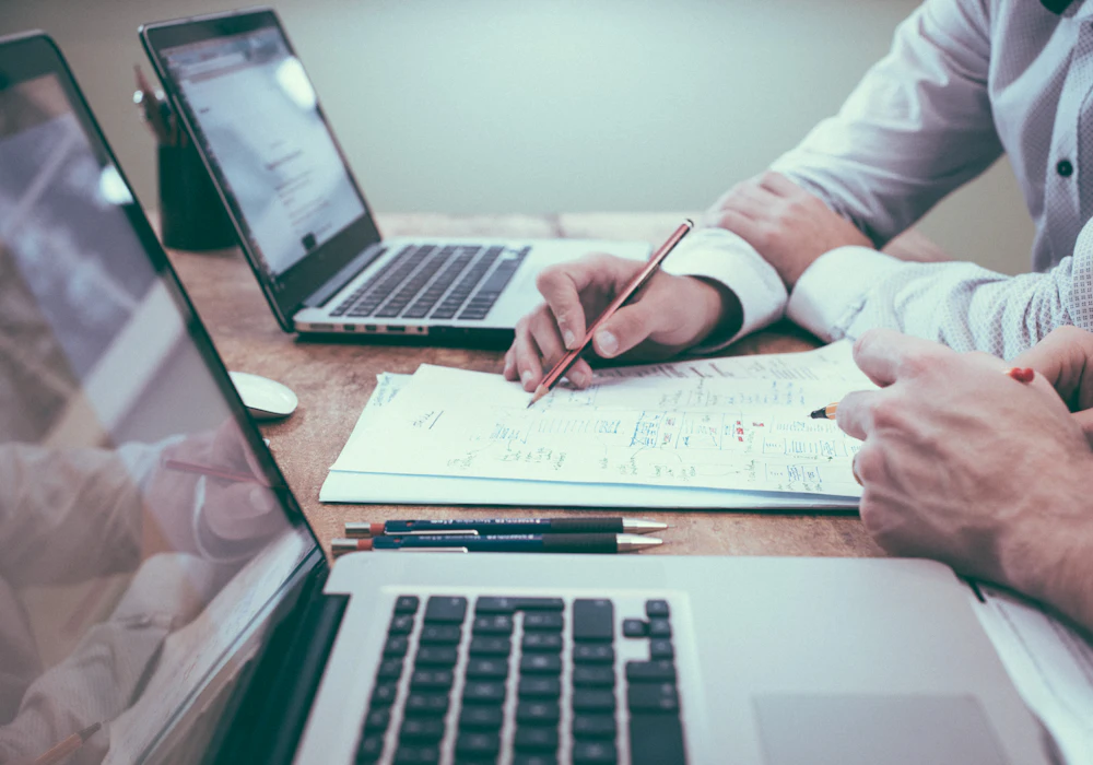 A payroll administrator checking inputs on a laptop beside handwritten notes